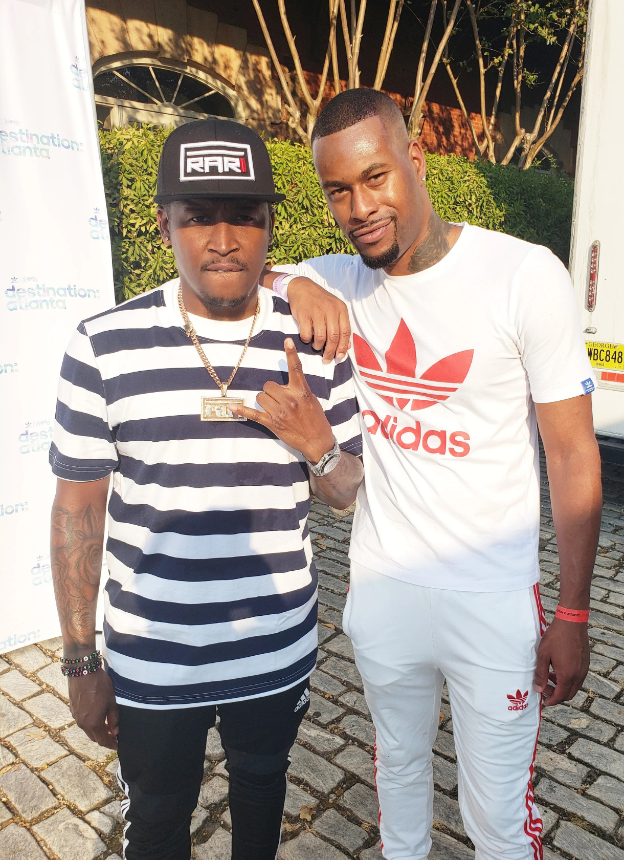 Two men stand together outdoors at a Destination Atlanta event, posing for a photo in front of a branded backdrop.