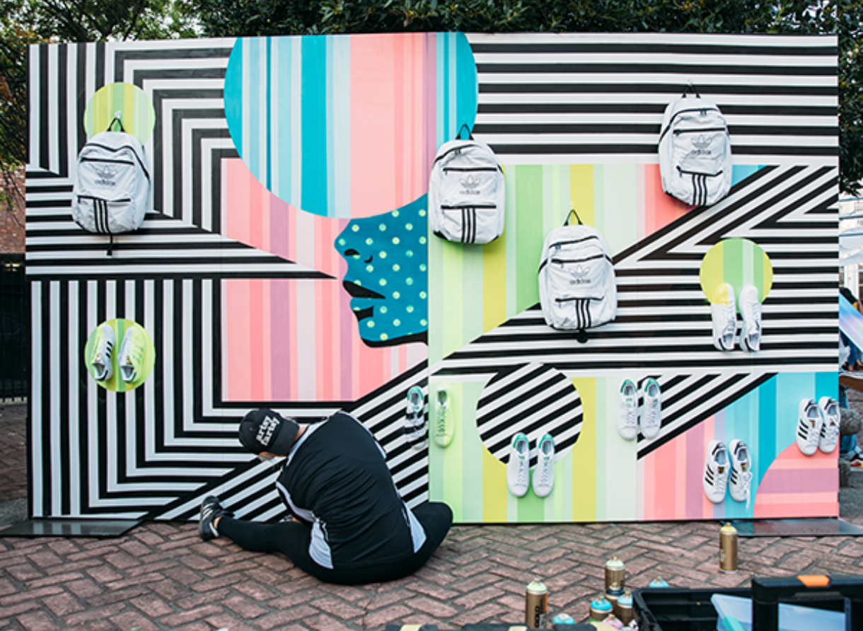 A large outdoor Adidas Journeys art installation featuring bold patterns, displayed shoes, and backpacks.