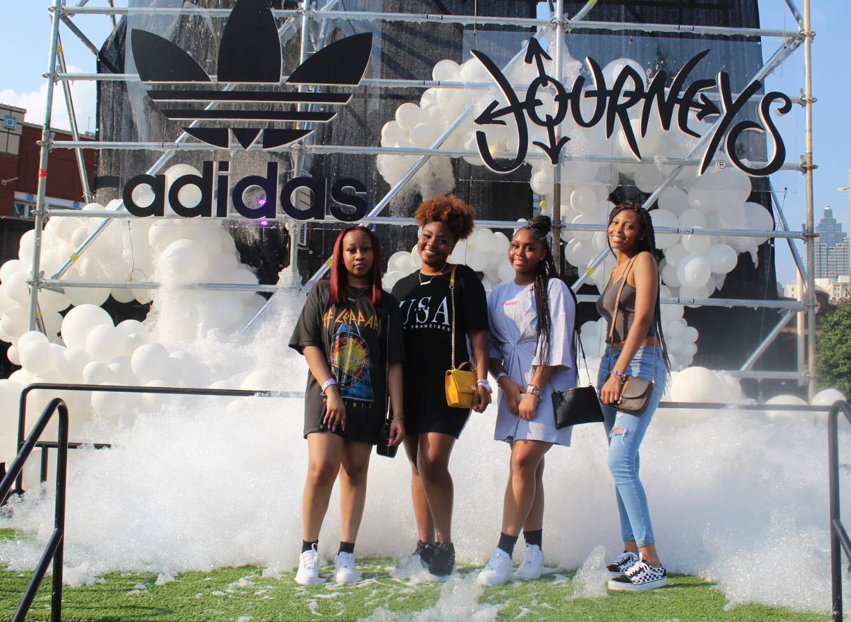 Four people pose smiling in front of an Adidas Journeys installation surrounded by foam.