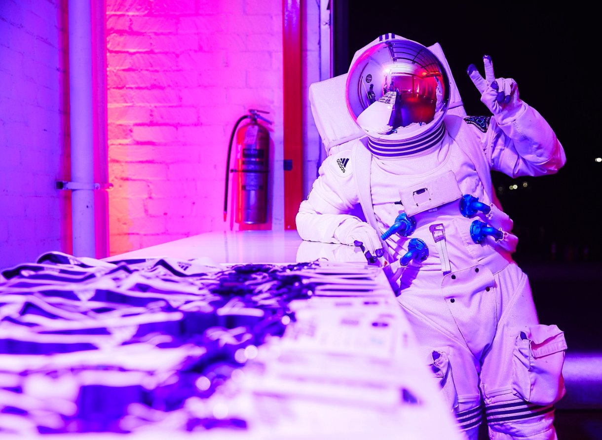 Performer dressed as an astronaut poses behind branded merchandise at the Goodbye Gravity event.
