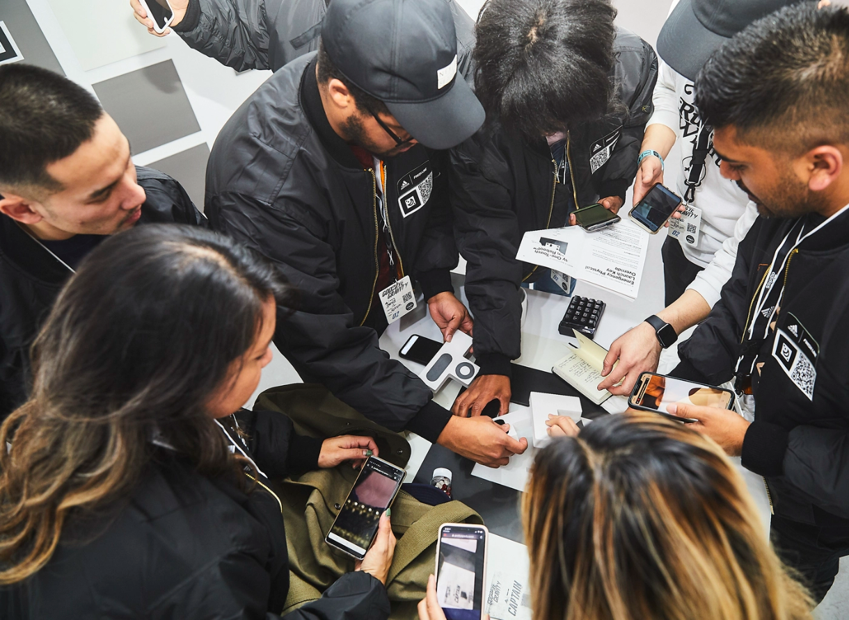Group of attendees collaborate around an interactive table using mobile devices at Goodbye Gravity.