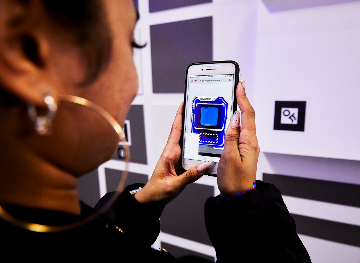 Guest uses a smartphone to interact with a QR-coded installation wall at Goodbye Gravity.