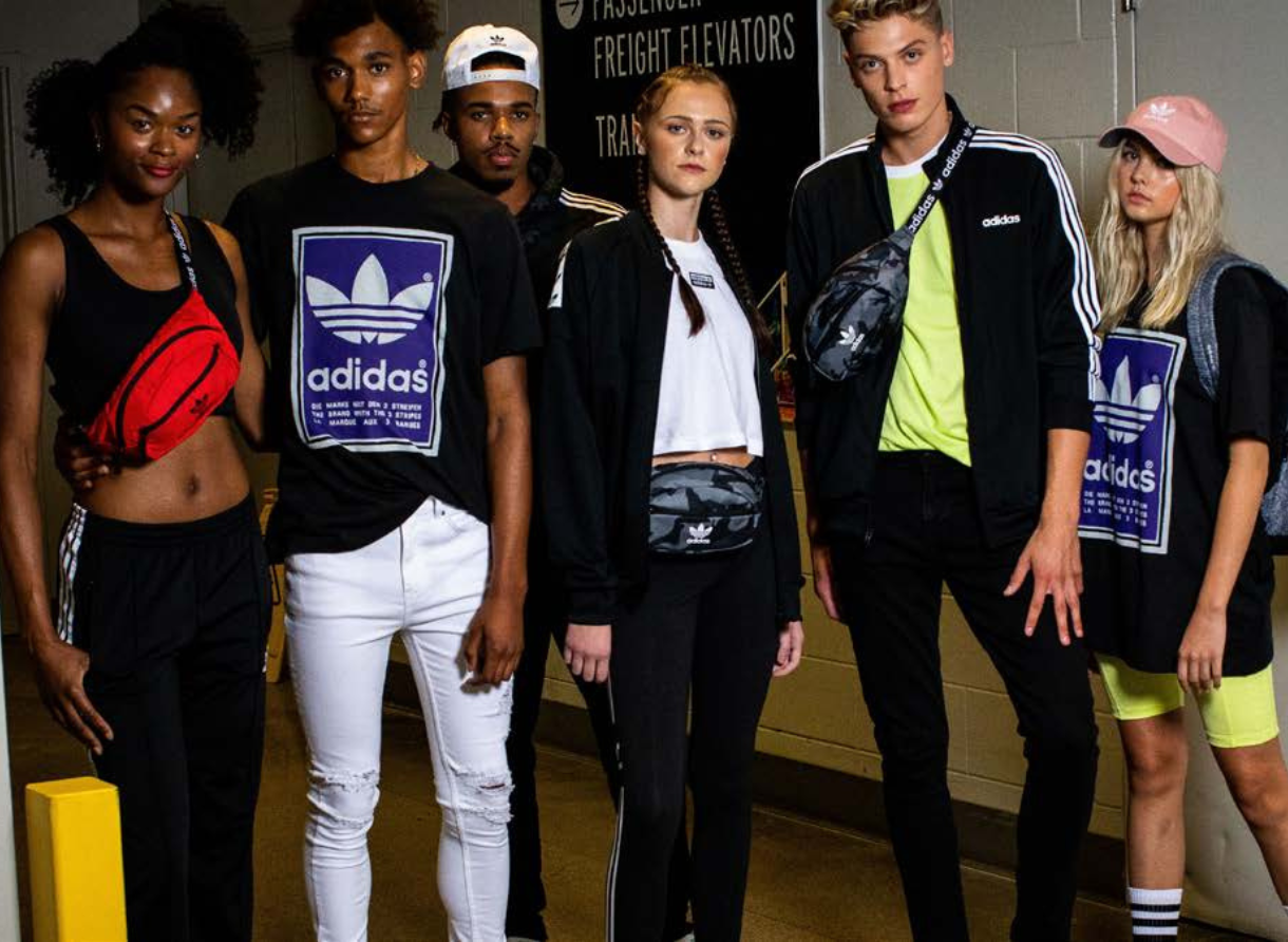 Group of runway models wearing adidas apparel pose backstage before a fashion show.