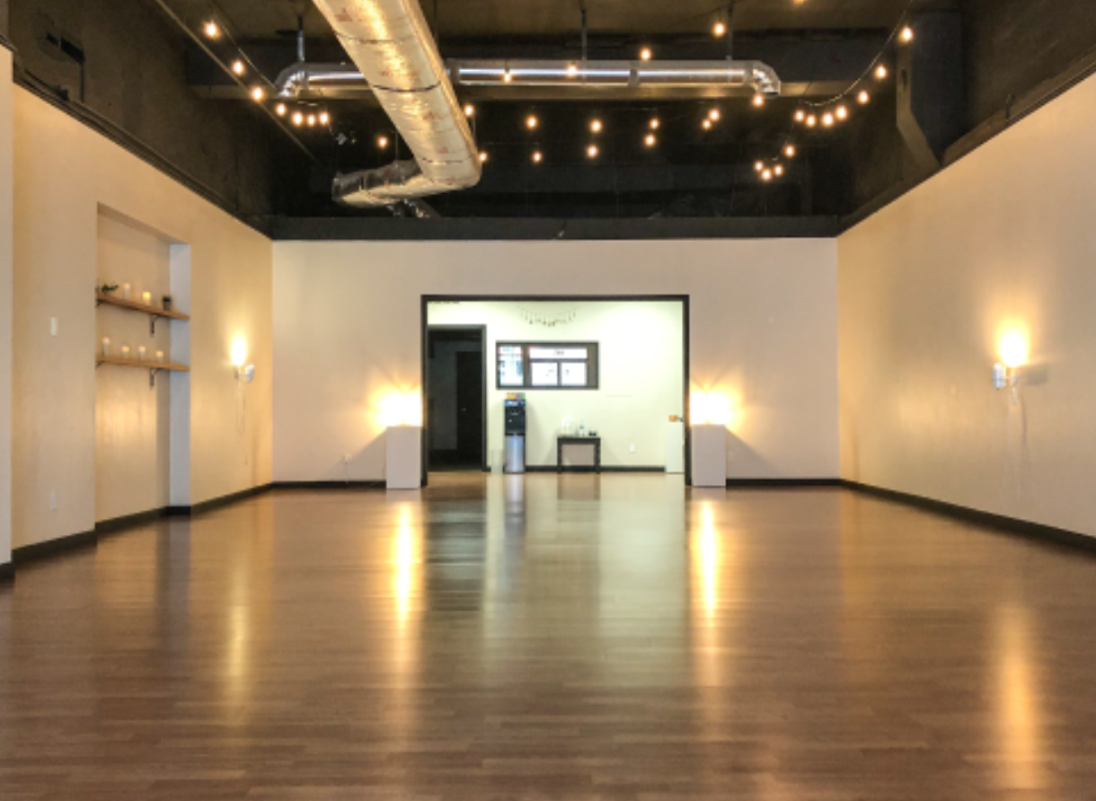 Wide view of finished Kove Yoga studio with wood floors, string lights, and open practice space.