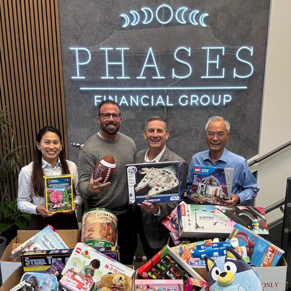 Phases Financial Group team members standing behind boxes of donated toys inside the Phases office.