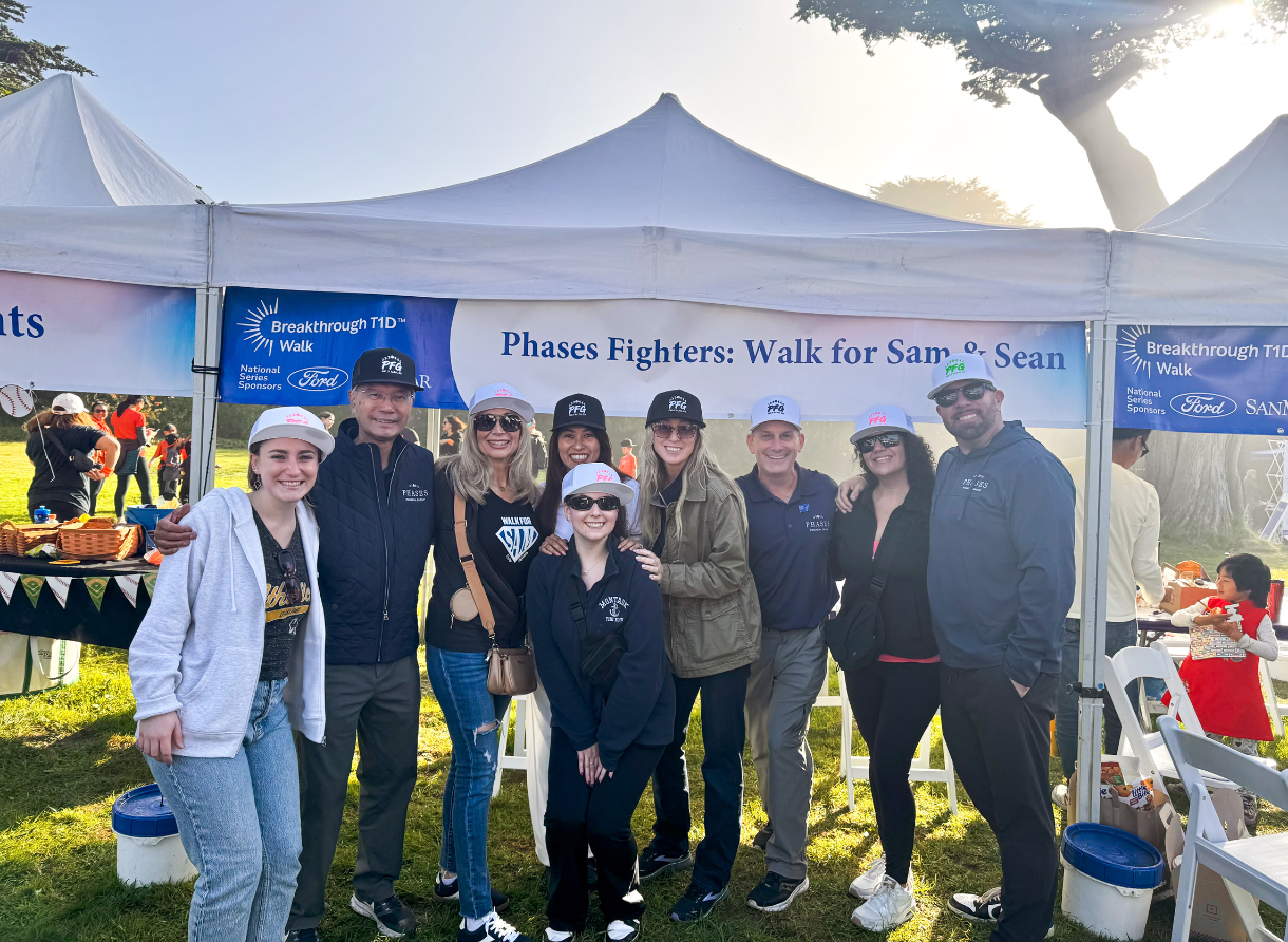 Phases Financial Group team members and family standing together beneath a “Phases Fighters” tent at the Breakthrough T1D Walk.
