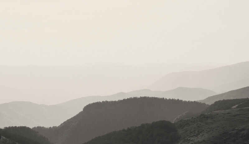 Soft, layered mountain ridgelines fading into the distance under a pale sky.